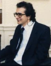 Charles Krauthammer seated in a suit and tie, smiling in a candid portrait photo.