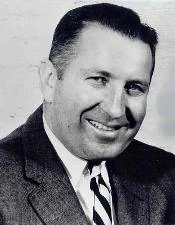 Black-and-white portrait of Charles Francis Feeney smiling in a suit and tie
